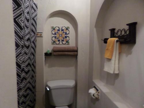 une petite salle de bains avec des toilettes et une photo sur le mur. dans l'établissement Hotel Casa del Cerro, à Antigua Guatemala