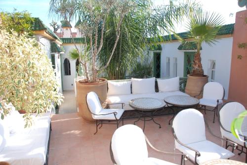 a patio with a white couch and chairs and trees at Riad Celia in Marrakech