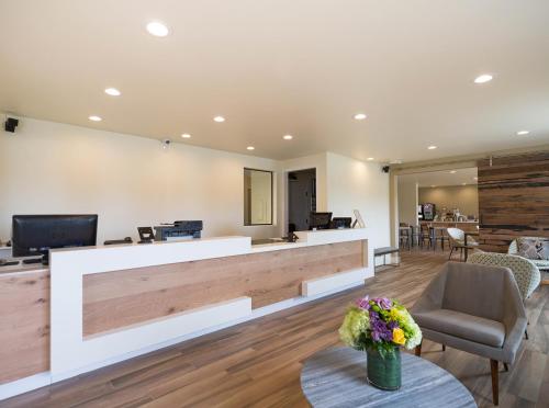a lobby with a reception desk with flowers on a table at Hotel Focus SFO in South San Francisco