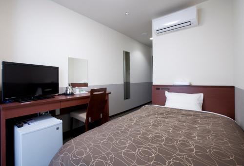 a bedroom with a bed and a desk and a television at Natural SPA, Kanazawa Hotel Yumenoyu in Kanazawa