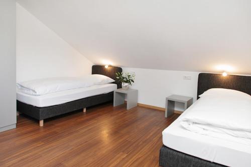 two beds in a room with wooden floors at Pension Arkade in Neckarsulm