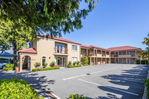 a large apartment building with a parking lot at Roma On Riccarton Motel in Christchurch