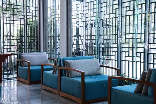 a waiting room with blue chairs and large windows at Fusion Suites Phuket Patong in Patong Beach