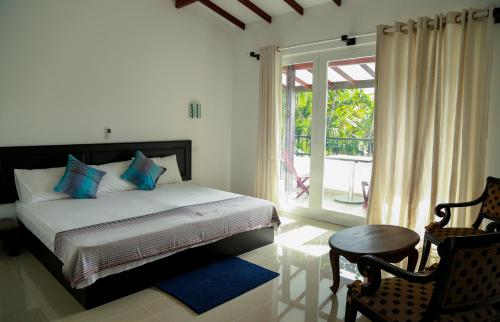 a bedroom with a bed and a window and a chair at Hikka Nature Villa in Hikkaduwa