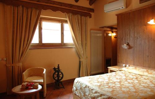 a bedroom with a bed and a window and a chair at Le Village in Montjovet