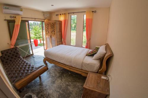 a bedroom with a bed and a couch and a window at El Greco Bungalows Koh Lanta in Ko Lanta