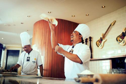 two chefs standing in a kitchen preparing food at Hard Rock Hotel Penang in Batu Ferringhi
