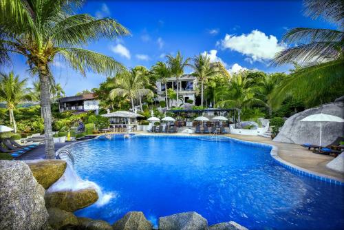 a resort swimming pool with palm trees in the background at Jamahkiri Dive Resort & Spa in Koh Tao