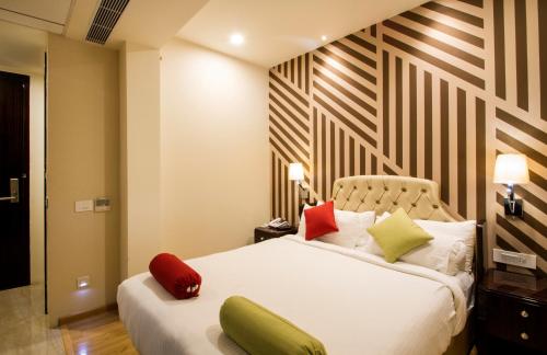 a bedroom with a white bed with red and green pillows at Art Boutique Hotel Gachibowli in Hyderabad