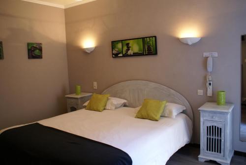 a bedroom with a white bed with two night stands at Le Petit Manoir Hotel Provence in Les Angles Gard