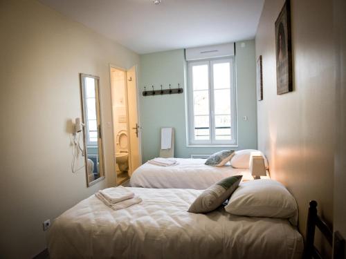 a bedroom with two beds and a mirror at Logis Hotel Restaurant Le Relais Fleuri in Vervins
