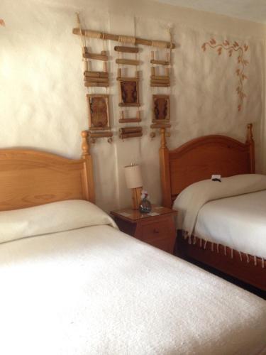 a bedroom with two beds and a table with a lamp at Hotel El Portón in Tenancingo de Degollado