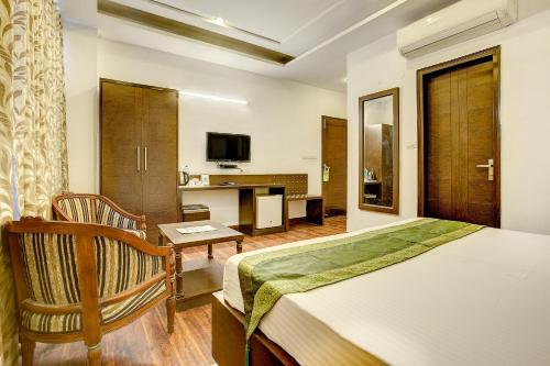 a bedroom with a bed and a desk and a television at Treebo C T International in New Delhi
