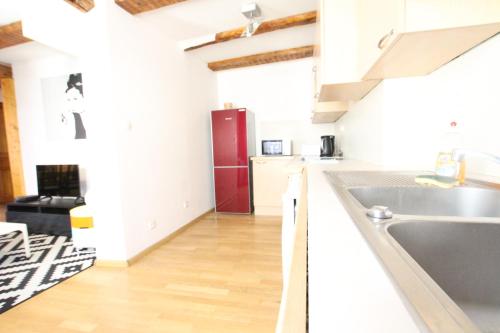 La cuisine est équipée de placards blancs et d'un réfrigérateur rouge. dans l'établissement Colmar Historic Center - Alsacian Appartement PETITE VENISE 1 - BookingAlsace, à Colmar