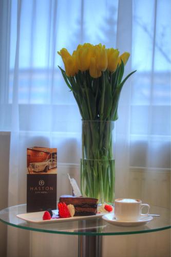 a vase of yellow tulips sitting on a glass table with a cup at Haston City Hotel in Wrocław