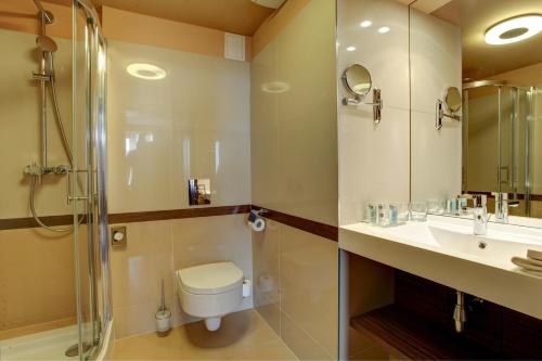 a bathroom with a toilet and a sink and a shower at Haston City Hotel in Wrocław