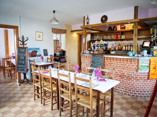 a restaurant with a table and chairs and a bar at Logis Hotel Restaurant Le Relais Fleuri in Vervins