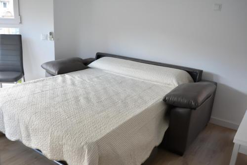 Cama en habitación con colcha blanca en Apartamentos San Agustín en Murcia