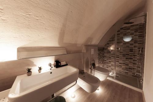 La salle de bains blanche est pourvue d'un lavabo et de toilettes. dans l'établissement La Chiocciola sui Sassi, à Matera