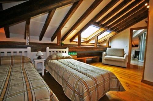 a bedroom with two beds and a chair in a room at Albergue Turístico Valdebaró in Camaleño