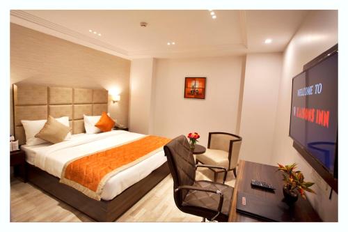 a hotel room with a bed and a flat screen tv at Kaisons Inn (Near Apollo Hospital) in New Delhi