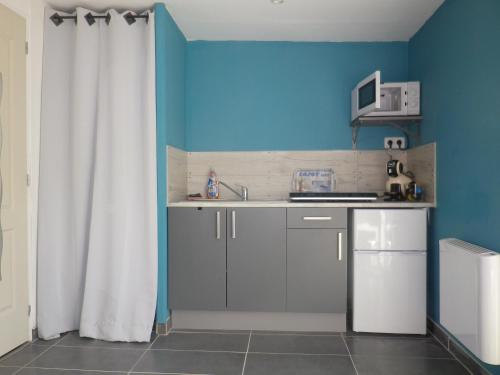 - une cuisine avec un évier et un mur bleu dans l'établissement Chez Isa, à Saint-Martin-Boulogne