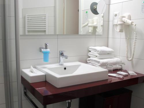ein Badezimmer mit einem Waschbecken, einem Spiegel und Handtüchern in der Unterkunft Kurhaus Devin in Stralsund