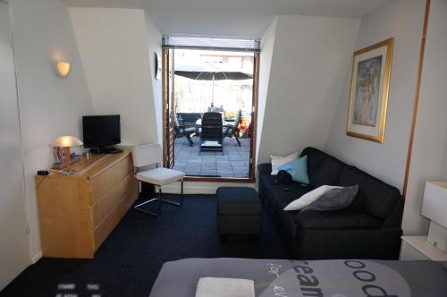 a living room with a couch and a tv and a table at Amsterdam Roof Terrace B&B in Amsterdam