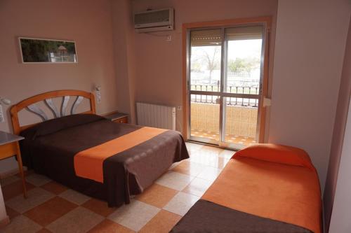 a bedroom with a bed and a window with a balcony at Hostal Alamare in Seville