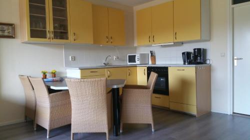 una cocina con armarios amarillos y una mesa con sillas en de Zanding en Oost-Vlieland