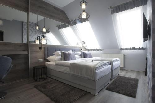 um quarto com uma grande cama branca e janelas em Hotel Talizmán em Kecskemét