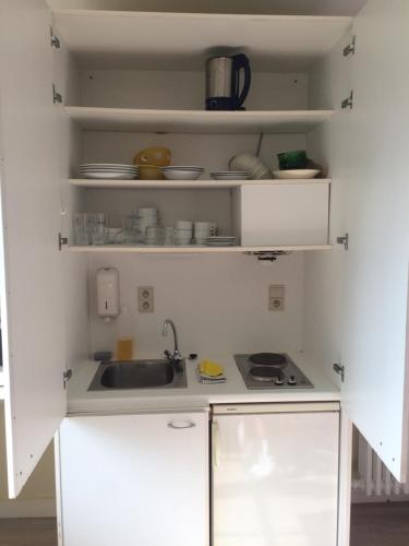 a kitchen with white cabinets and a sink at Logies De Wandelaar in Westende-Bad
