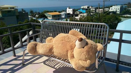 a large teddy bear sitting on a bench on a balcony at Color Rainbow Home in Taimali