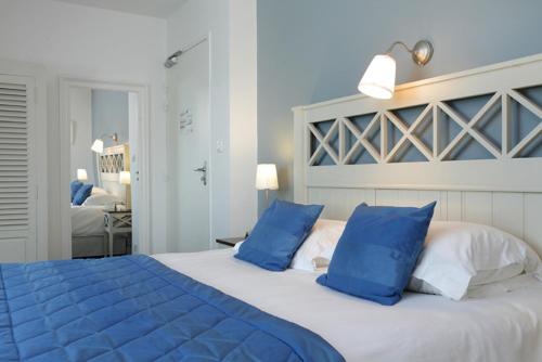 a blue bed with blue pillows in a bedroom at Logis Hotel, restaurant et spa Le Relais De Broceliande in Paimpont