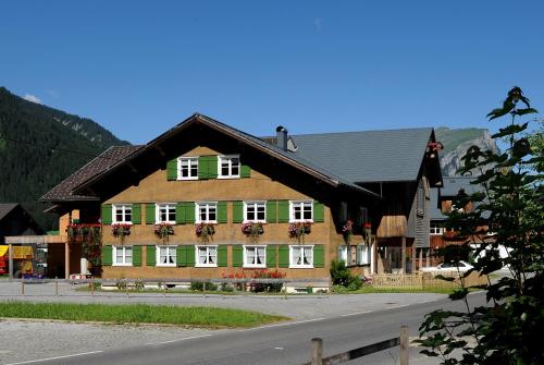 a large building with green and white windows and a road at Ferienbauernhof Erath in Schoppernau