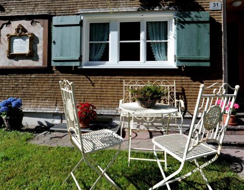 two chairs and a table in front of a house at Ferienbauernhof Erath in Schoppernau