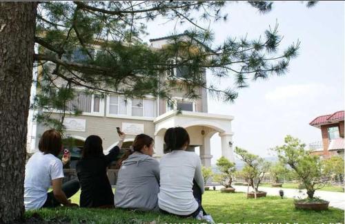 four women sitting on the grass in front of a house at Songfeng Xiuxian Homestay in Puli
