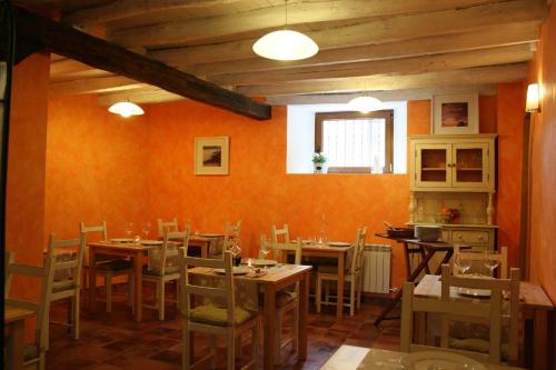 una sala da pranzo con pareti arancioni e tavoli e sedie in legno di La Nogala a Dobro