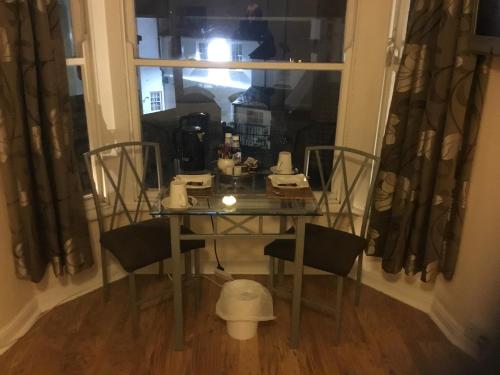 a glass table and chairs in a room with a window at The Dock Inn in Penzance