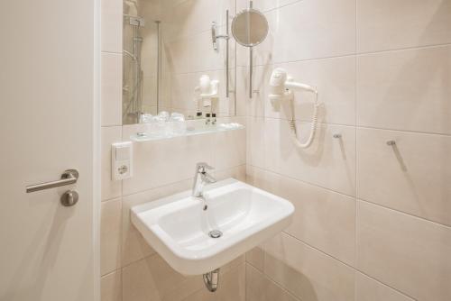 a white bathroom with a sink and a shower at BSW Hotel Isarwinkel in Bad Tölz
