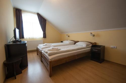 a bedroom with two beds and a television in it at Sziklakert Fogadó in Sâncrai