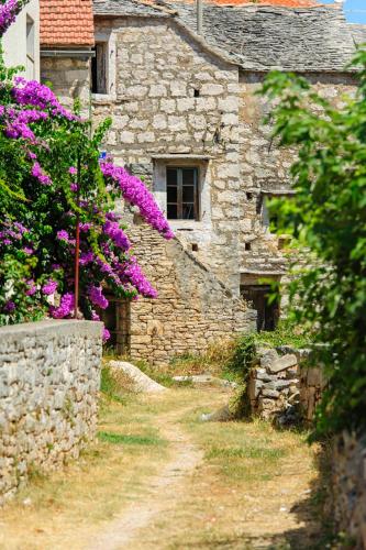 a stone building with purple flowers in front of it at Apartment Fana in Grohote