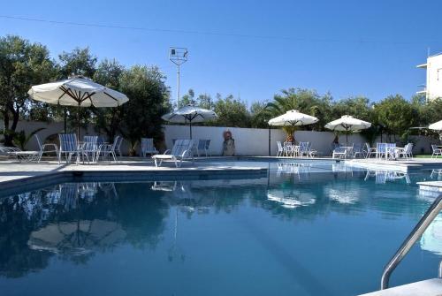 a swimming pool with tables and chairs and umbrellas at Klonos Anna in Aegina Town