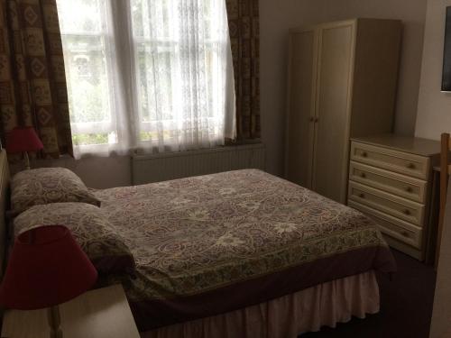 a bedroom with a bed and a dresser and a window at St. James's Guest House in London