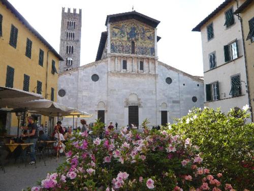 un bâtiment avec une tour d'horloge et quelques fleurs dans l'établissement Casa degli angeli, à Lucques