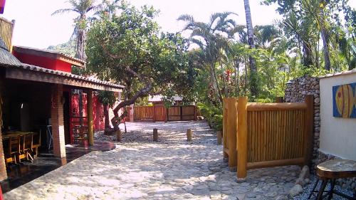 a courtyard of a house with a fence and trees at Mandacaru Chalés e Suítes Itamambuca in Ubatuba