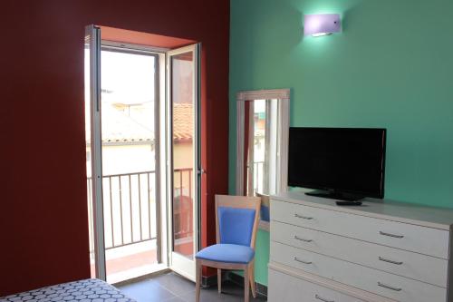 a bedroom with a tv and a dresser with a window at CasaTua Punta Secca in Punta Secca