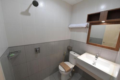 a bathroom with a toilet and a sink and a mirror at Avon's Residence in Manado