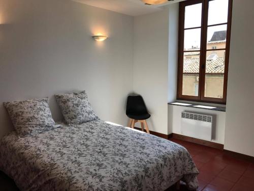une chambre avec un lit, une fenêtre et une chaise dans l'établissement Appartement au coeur de Carcassonne, à Carcassonne