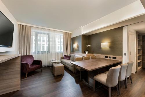 a living room with a wooden table and chairs at Wyndham Grand Salzburg Conference Centre in Salzburg